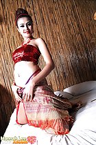 Kneeling on bed with thumbs in sarong in crop top