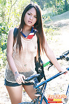 Standing beside bicycle long hair wearing string vest in shorts