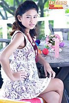 Seated at table wearing dress hand on hip