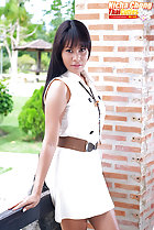 Wearing white dress standing against fence